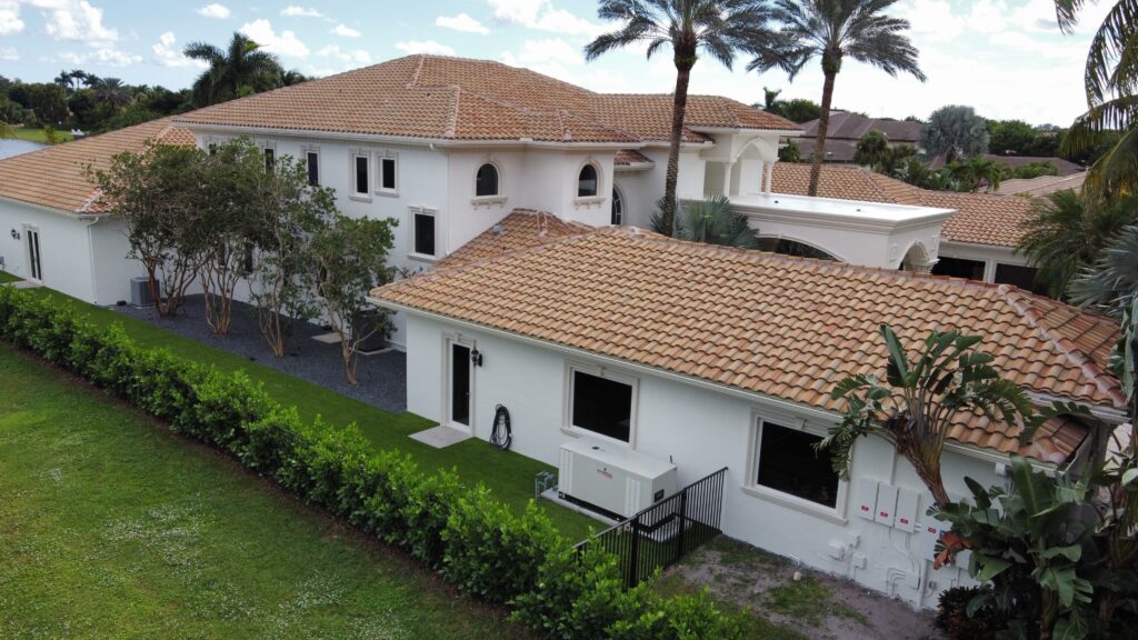 Aerial view of a freshly painted white estate home with a terracotta roof